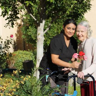 A caregiver and an elderly woman enjoying time together in the garden.