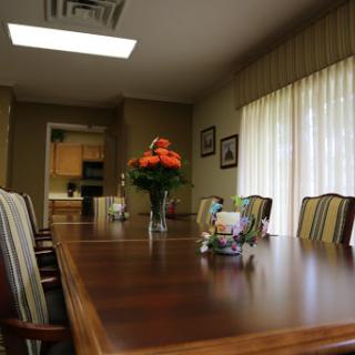A spacious and well-lit conference room set up for meetings, featuring a long wooden table and elegant decor.