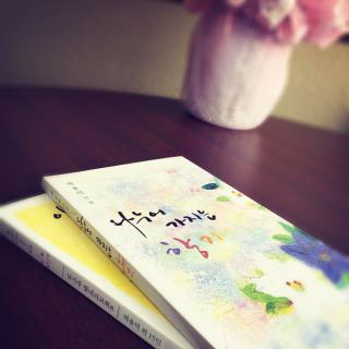 Two books resting on a table beside a decorative flower vase.