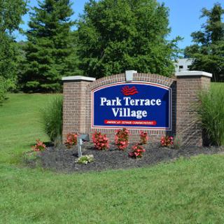 Entrance sign for Park Terrace Village, surrounded by greenery and flowers.