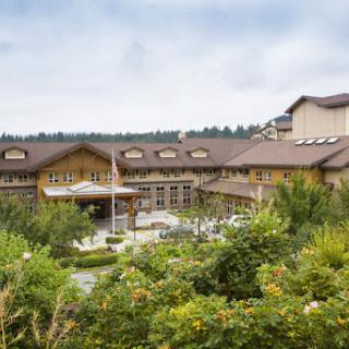 A scenic view of a hotel surrounded by lush greenery and a cloudy sky.