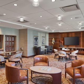 A modern lounge area featuring comfortable seating and a large screen, designed for meetings and relaxation.