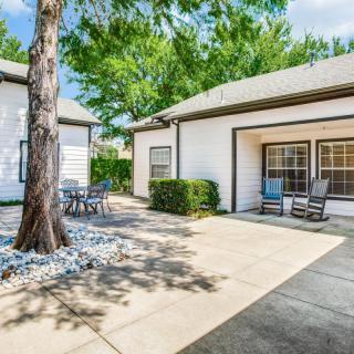 A sunny backyard patio with outdoor furniture, featuring a tree beside a house.