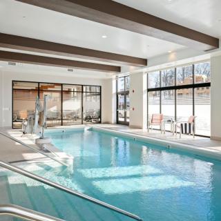A bright and modern indoor swimming pool with large windows allowing natural light to flood the space.