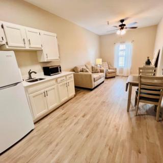 A cozy, open-plan living space featuring a kitchen, dining area, and lounge with wood flooring.