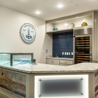 A modern kitchen interior featuring a countertop, built-in wine cooler, and wall clock.