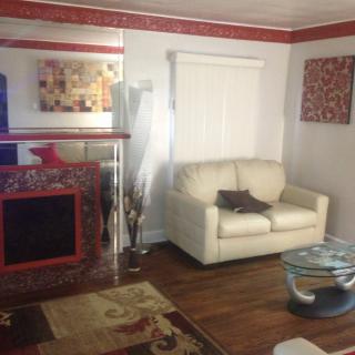 A cozy living room with a white sofa, decorative fireplace, and colorful artwork on the walls.