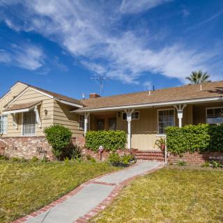 A suburban house with a well-maintained lawn and clear blue sky.