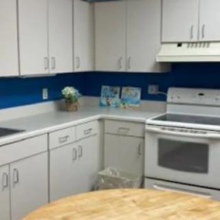 A modern kitchen with white cabinets, a stove, and a blue accent wall.