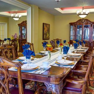 A beautifully set dining table with blue napkins and elegant wooden furniture in a well-decorated room.