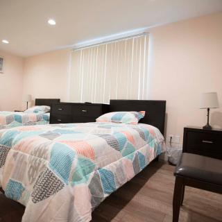 A cozy bedroom with two beds featuring colorful geometric bedding, complemented by matching nightstands and lamps.