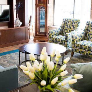 A stylish living room with patterned armchairs, a round coffee table, and a bouquet of white tulips.