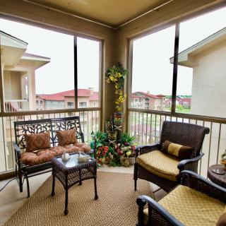 A cozy balcony with comfortable seating and decorative plants, overlooking neighboring buildings.