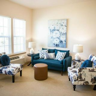 A cozy living room with a teal sofa, patterned armchairs, and soft lighting.
