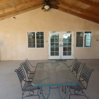 A covered patio with a rectangular table and chairs beneath a ceiling fan.