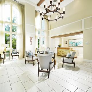 A spacious and elegantly designed lobby area featuring comfortable seating, a grand chandelier, and abundant natural light.