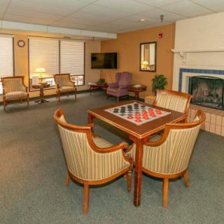 A cozy lounge area featuring a chessboard table, comfortable chairs, a fireplace, and a television.