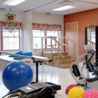 A rehabilitation room filled with various exercise equipment, including stability balls and therapy tools.