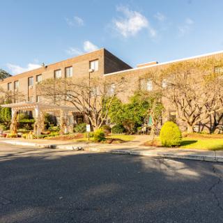 A modern building surrounded by lush greenery and a clear blue sky.