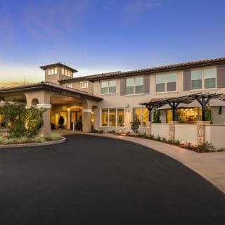 A large residential house with a well-maintained exterior and spacious driveway, photographed at twilight.