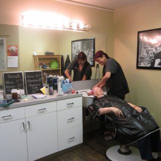 A stylist washing a client's hair in a barber shop.