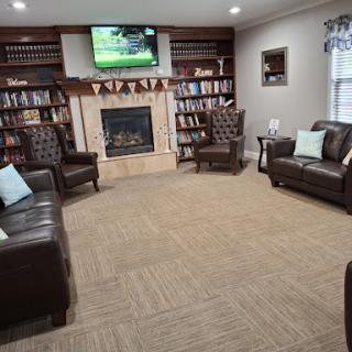 A cozy living room with comfortable seating, a fireplace, and shelves filled with books, perfect for relaxation.