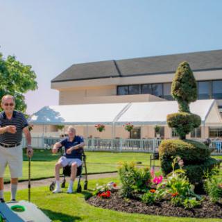 A sunny day in the garden with people enjoying leisure activities near a topiary.