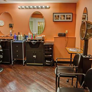 A cozy hair salon interior featuring styling stations with mirrors and chairs, surrounded by a collection of hair care products.