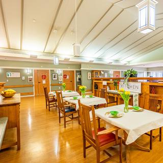 A well-lit dining area with neatly arranged tables and decorative plants.