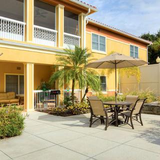 A sunny patio with outdoor seating and an umbrella next to a building.