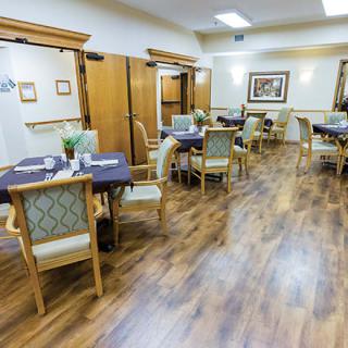 A cozy dining room with neatly arranged tables and chairs on a wooden floor.