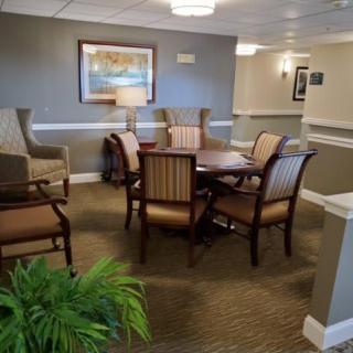 A cozy lobby area with a table and chairs, adorned with artwork and lighting.