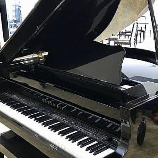 A grand piano with its lid open, showcasing the keyboard.