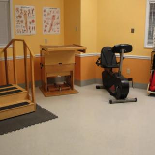 A rehabilitation room equipped with therapy equipment including an exercise bike and stairs.