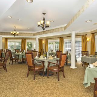 An elegant dining room with neatly arranged tables and chairs, featuring chandeliers and decorative curtains.
