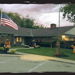 A beautifully landscaped residence with autumn decorations and an American flag waving in the breeze.