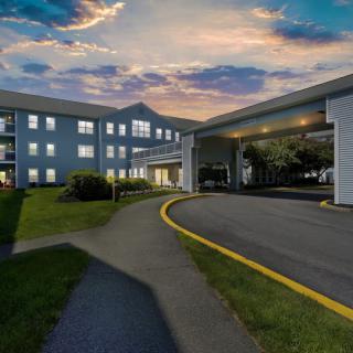 A nighttime view of a hotel entrance with a curved driveway and illuminated windows.