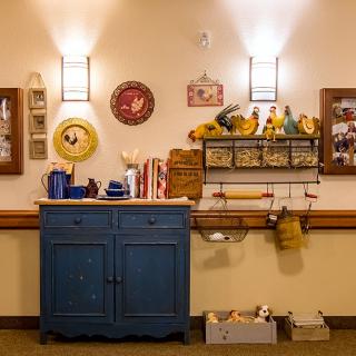 A cozy, vintage-themed kitchen corner with a blue cabinet and various decorations adorning the wall.