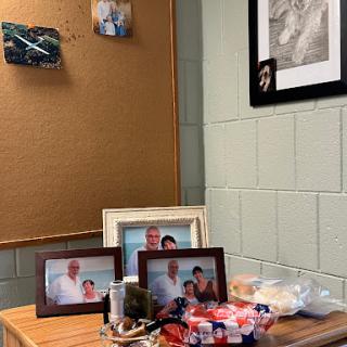 A cozy corner of an office space featuring family photos, decorative items, and a bulletin board.