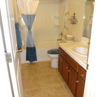 A neatly arranged bathroom with a sink, toilet, and bathtub, featuring a shower curtain and tiled floor.