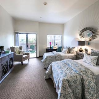 A well-decorated bedroom featuring twin beds, a large window, and stylish furnishings.