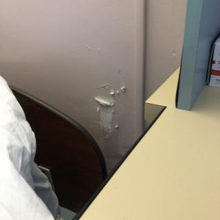 A damaged wall corner near an office desk.