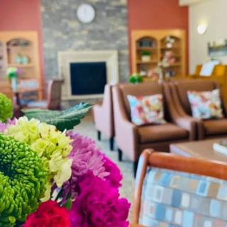 A cozy lobby with vibrant flowers and a welcoming seating area by the fireplace.