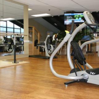 A modern gym interior with exercise machines and a wooden floor.