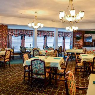 A cozy dining room with elegant chandeliers and decorated tables.