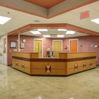 An empty hospital reception area with a central desk and multiple doors.