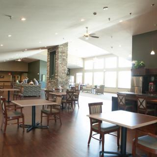 A spacious restaurant interior with tables and chairs arranged in a well-lit dining area.