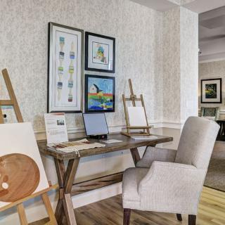 A cozy art studio with easels, paintings, and a comfortable chair.