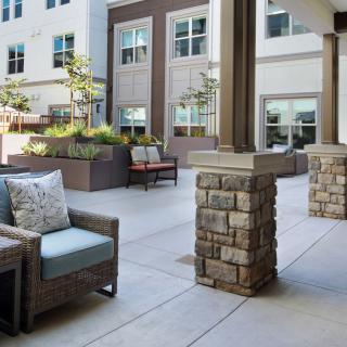 A modern patio area with comfortable seating and landscaped planters, surrounded by building exteriors.