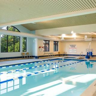An indoor swimming pool with multiple lanes and natural light streaming in through large windows.